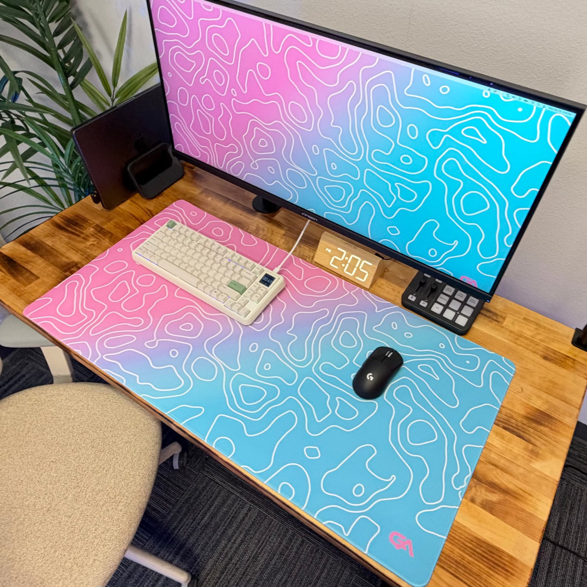 Topo Gradient desk mat in pink and blue on a wood desk with a mechanical keyboard and gaming mouse